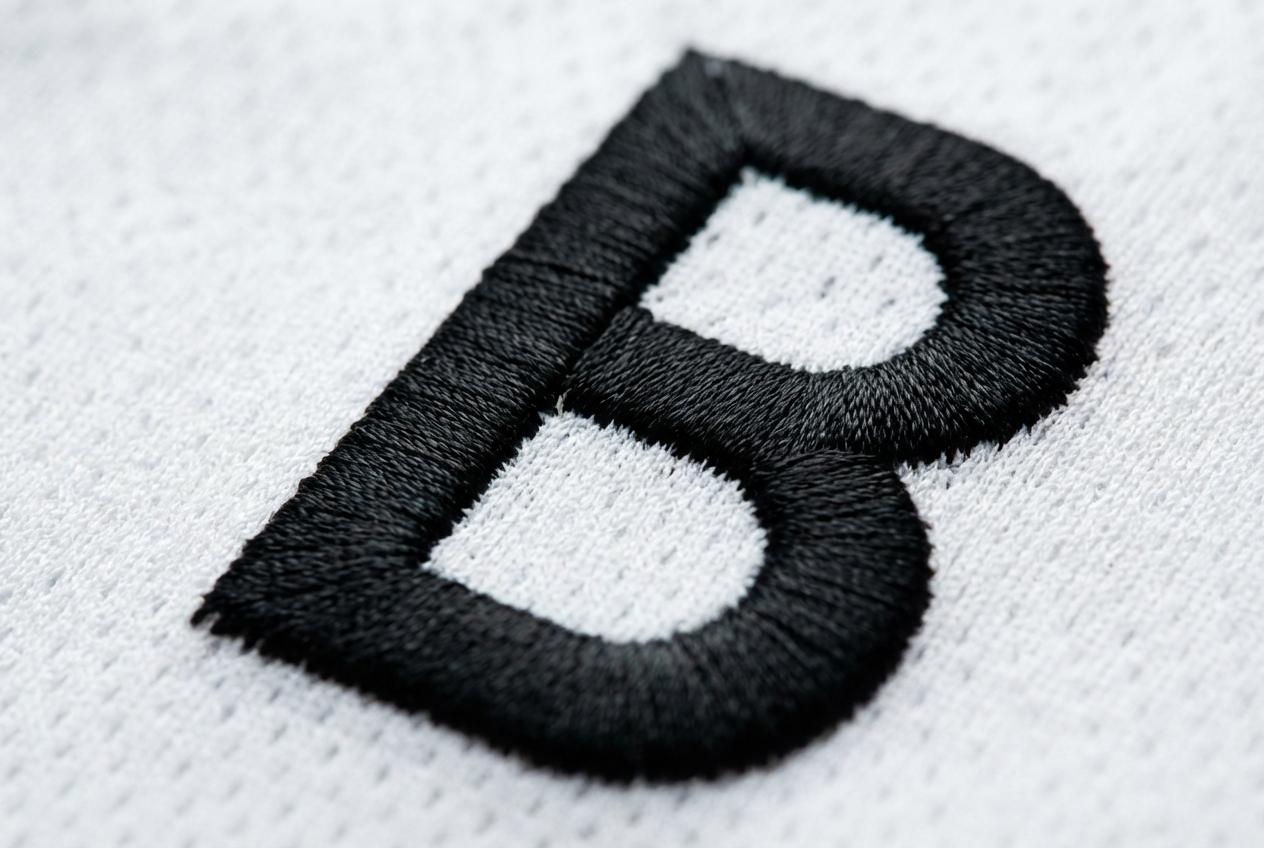 Close-up of black letter B stitched on white fabric