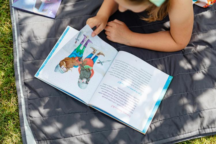 Child Reading a Book on a Blanket